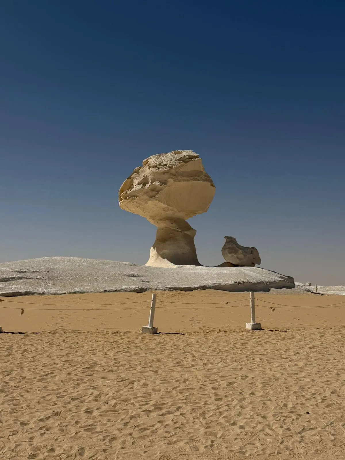 A chalk rock formation in the White Desert under a deep blue sky