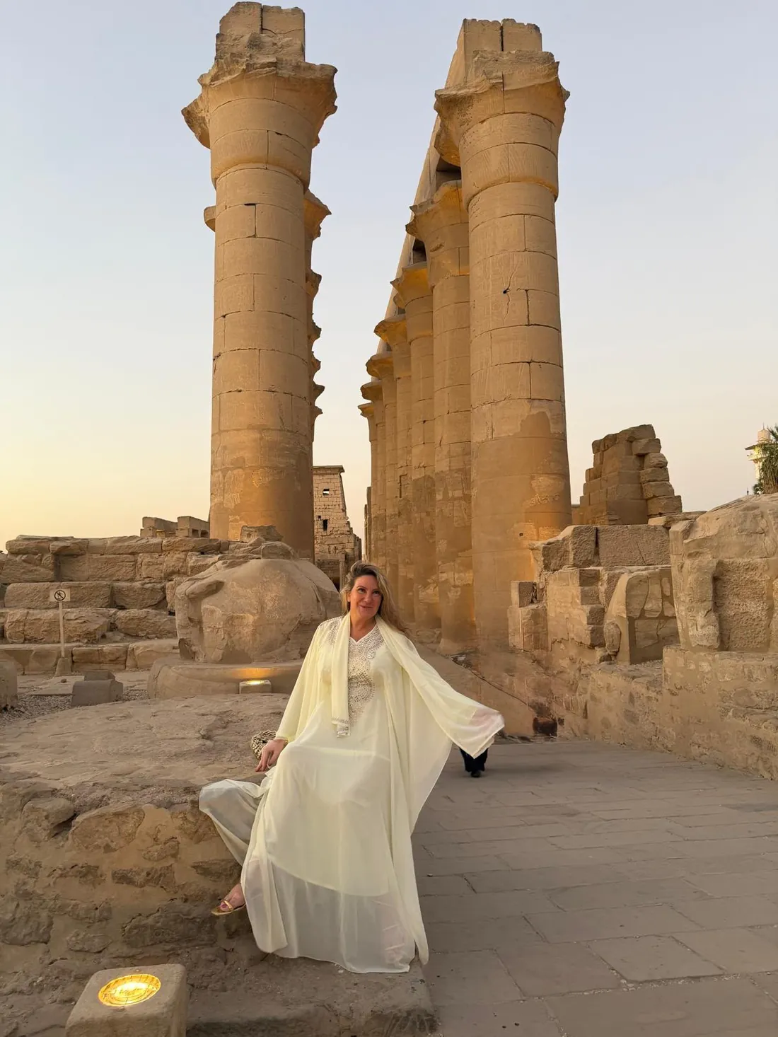 Zhivka Hristova in white among the temple columns of Luxor at dusk